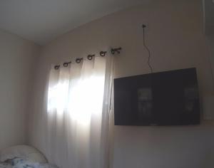 ein Schlafzimmer mit einem Fenster mit einem Vorhang und einem TV in der Unterkunft Suíte Rio de Ondas 1 in Barreiras