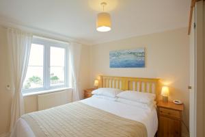 a bedroom with a bed with white sheets and two windows at Compass Point in Carbis Bay
