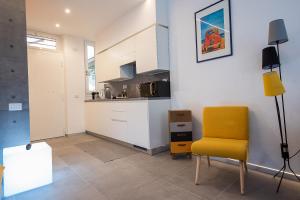 uma sala de estar com uma cadeira amarela e uma cozinha em Cosy studio in the greenest corner of Trastevere em Roma