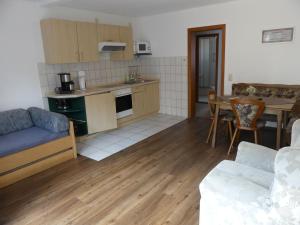 eine Küche und ein Wohnzimmer mit einem Sofa und einem Tisch in der Unterkunft Gästehaus Bommelsen in Walsrode