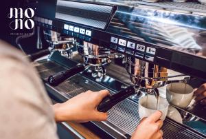 a person is making coffee in a espresso machine at Rost Apartments in Bielsko-Biała