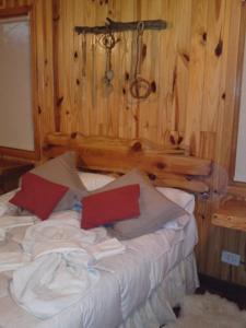 Cama en habitación con pared de madera en Parajes del lejano sur cabaña El Cardo in 