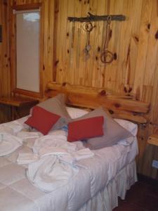 a bedroom with a bed with white sheets and red pillows at Parajes del lejano sur cabaña El Cardo in Moquehue