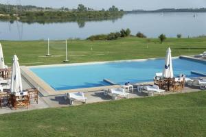 a swimming pool with chairs and umbrellas next to a lake at San Isidro Hotel in Mercedes