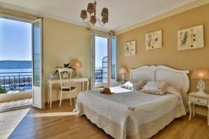 a bedroom with a bed and a desk and a balcony at Hotel De La Darse in Villefranche-sur-Mer