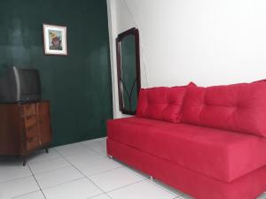 a red couch in a living room with a tv at Casa acolhedora - aluguel por temporada in Lençóis