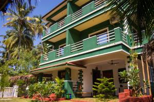 um edifício verde e branco com palmeiras em Green Nest Hostel, Baga - Arpora em Arpora