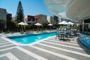 een zwembad met stoelen, tafels en parasols bij Evdokia Suites in Gouves