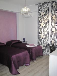 a room with two beds and a table with purple blankets at Bed & Breakfast Amari 58 in Palermo