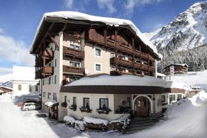 um grande edifício com neve nas montanhas em Hotel Bergland Superior em Sankt Leonhard im Pitztal