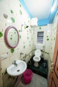 a bathroom with a sink and a toilet and a mirror at Tirupati Lodge NJP in Siliguri