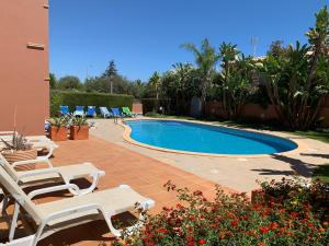 a swimming pool with lounge chairs next to a house at 2 Bedroom Apartment - Only 100 Metres From The Fabulous Meia Praia Beach in Meia Praia