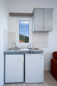 eine Küche mit weißen Schränken, einem Waschbecken und einem Fenster in der Unterkunft Dimitris Studios in Karavomylos