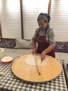 a woman cutting a wooden board on a table at Acrotel Sofia's Guest House in Sidherás