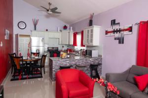 cocina y sala de estar con sillas rojas y mesa en The Oasis II, Caymanas Country Club, en Ellis Caymanas
