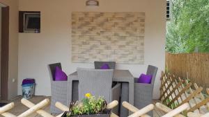 een patio met stoelen en een tafel met paarse kussens bij Kids' Paradise House in Balatonboglár