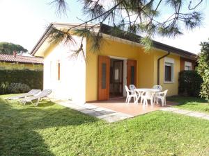 a small yellow house with a table and chairs at Villa Mughetto in Bibione