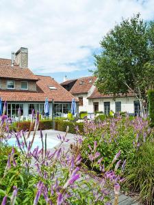 a garden with purple flowers in front of a house at Country House Duinhof in De Haan