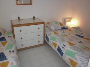 a small bedroom with a bed and a dresser at Aqua Plage in Cap d'Agde