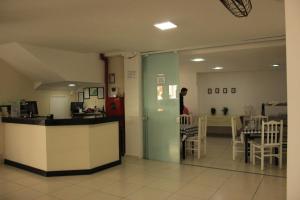 una persona parada en una habitación con mesa y sillas en Novo Hotel Douglas, en Balneário Camboriú