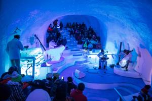 a crowd of people watching a performance in an ice cave at Chalet Fiocco di neve, Passo del Tonale in Passo del Tonale