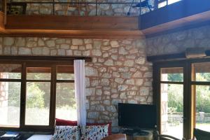 a living room with a tv and a stone wall at Elati Hills in Vytina