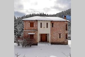 a brick house with a door in the snow at Elati Hills in Vitina