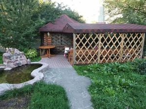 a wooden gazebo with a table and a pond at Куренiвський Двiр in Kyiv
