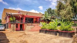 a red house with a porch and a driveway at Mahali Guesthouse, Makindye Hill in Kampala