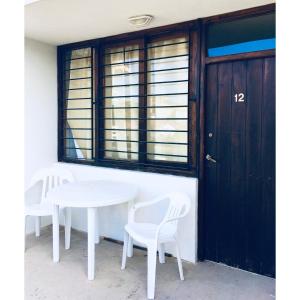 Una mesa blanca y dos sillas frente a una ventana. en Der Mar, en Villa Gesell