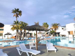 a pool at a resort with chairs and umbrellas at Puerta del Sol casa Lily Caleta de Fuste in Caleta De Fuste