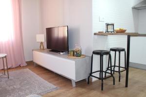 een woonkamer met 2 barkrukken en een tv op een kast bij Apartamento Botí in Cartagena