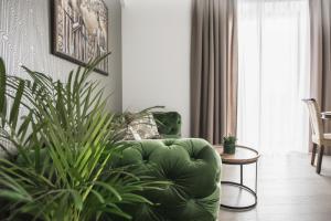 KM apartamentai في كاوناس: غرفة معيشة بها أريكة خضراء ومصنع