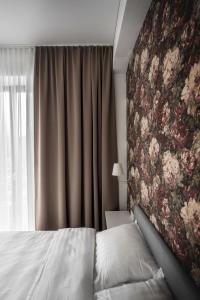 a bedroom with a bed and a floral wall at KM apartamentai in Kaunas