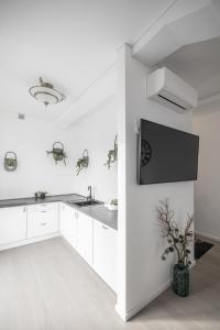 KM apartamentai في كاوناس: مطبخ مع دواليب بيضاء وتلفزيون على الحائط