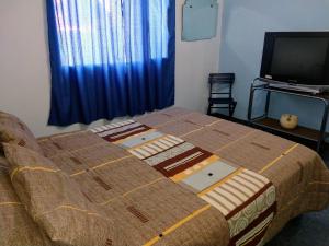 Cama en habitación con TV y colcha en Valle Encantado, en Monte Hermoso