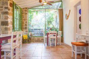 a room with a table and chairs and a window at Oliveyard Stone Built House- with pool non chlorin in Koskinou
