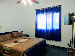 Un dormitorio con una cama y una cortina azul. en Valle Encantado, en Monte Hermoso