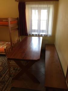 una mesa de madera y una silla en una habitación con ventana en Penzion ANTONIE, en Malá Morávka