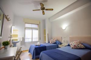 a bedroom with two beds and a ceiling fan at Hostal Guillot in Torremolinos