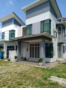 a large white house with green shutters at Ajmal Homestay @ Kota Bharu in Kota Bharu