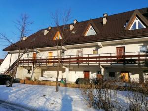een groot wit huis met een bruin dak in de sneeuw bij Apartament Elmal Pardałówka in Zakopane