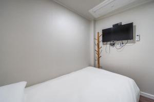 a white room with a bed and a tv on the wall at MAYONE HOTEL Myeongdong in Seoul