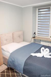 dos cisnes blancos sentados en una cama en un dormitorio en APARTAMENTY I POKOJE CENTRUM PIŁSUDSKIEGO Białystok, en Białystok