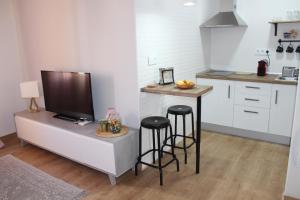 a kitchen with a bar with stools and a tv at Apartamento Botí in Cartagena