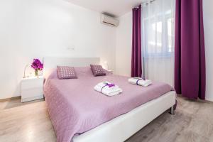 sypialnia z fioletowym łóżkiem z 2 ręcznikami w obiekcie Villa Mirta w mieście Tisno