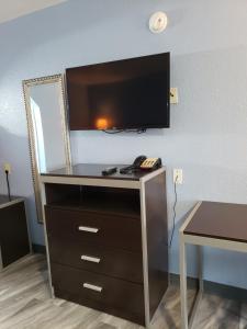a dresser with a flat screen tv on a wall at Regency Inn Motel by the Beach in Corpus Christi