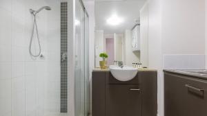 a white bathroom with a sink and a shower at Oaks Brisbane Casino Tower Suites in Brisbane