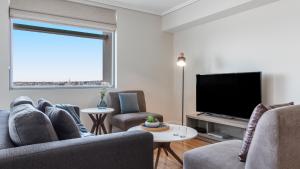 a living room with two chairs and a flat screen tv at Oaks Brisbane Casino Tower Suites in Brisbane