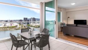 a living room with a dining room table and a balcony at Oaks Brisbane Casino Tower Suites in Brisbane